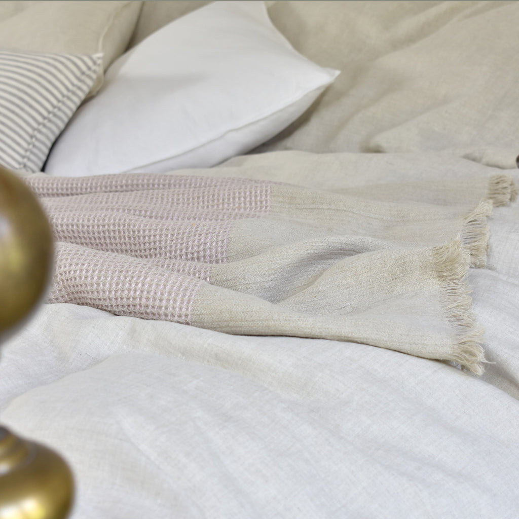 A Pale Pink Linen Blanket on A Bed with a White Linen Cushion