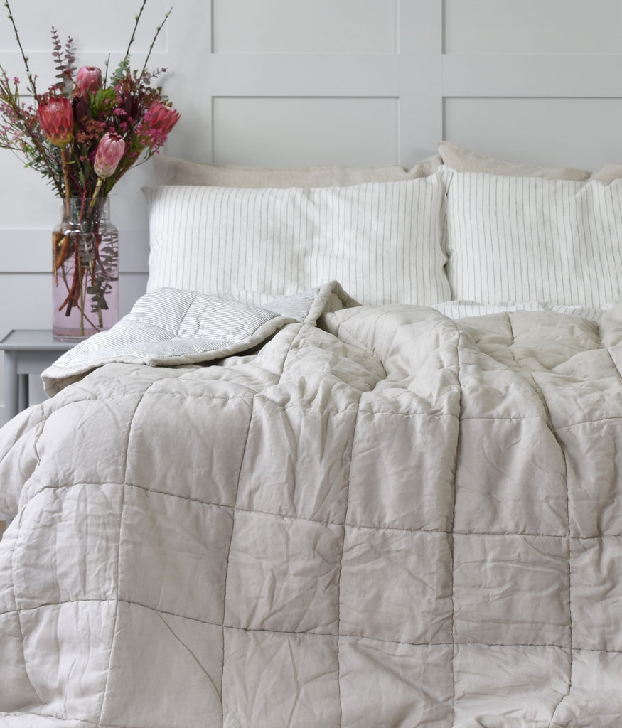 A Natural Linen Double Sided Quilt on a Bed with a Stripe Linen Duvet Cover Set