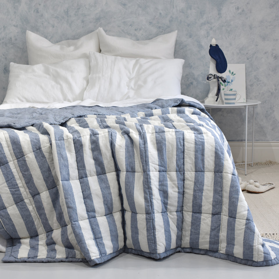A Blue Chambray Stripe Linen Quilted Bedspread on a Bed with White Linen Duvet Cover and Pillowcases
