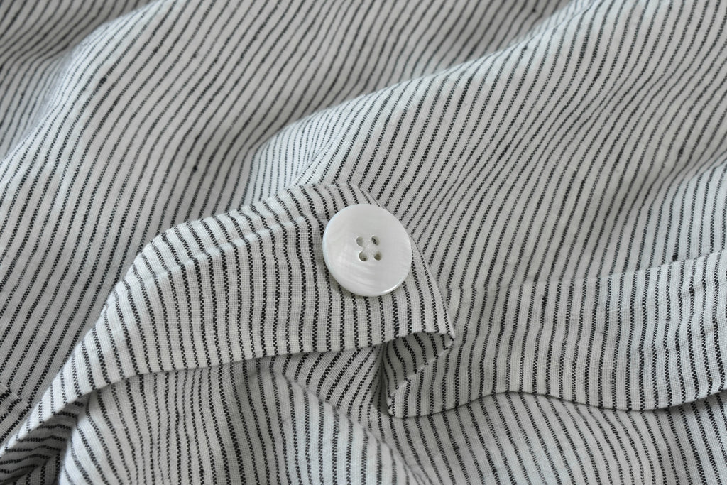 A close up picture of a Piece of Pinstripe Linen Duvet Cover and a Mother of Pearl Button