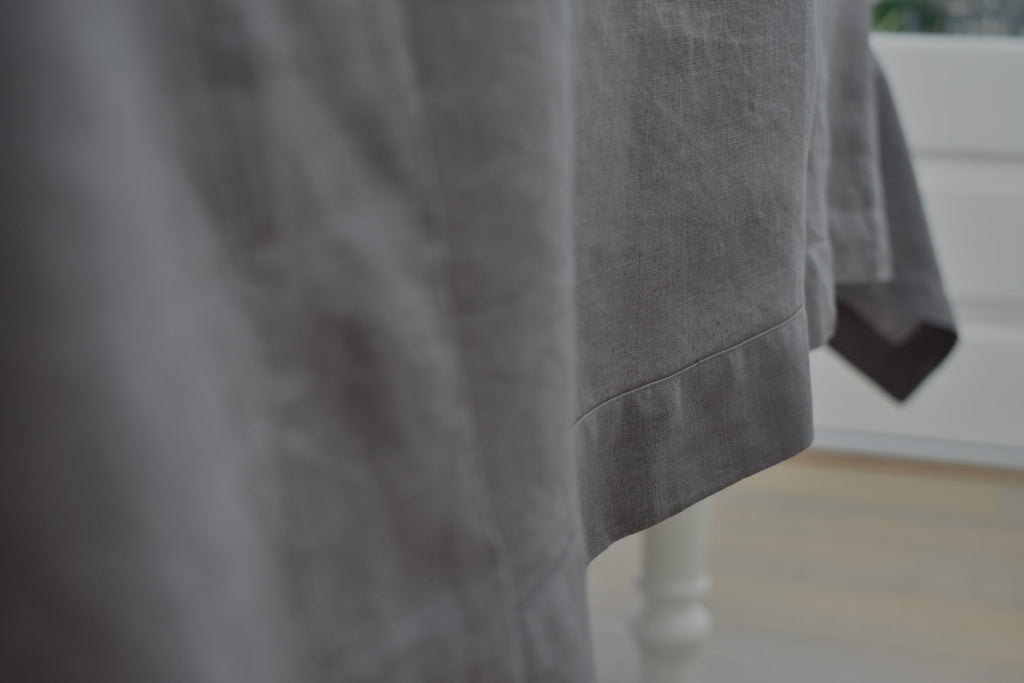 The edge of a Charcoal Grey Linen Tablecloth on a table