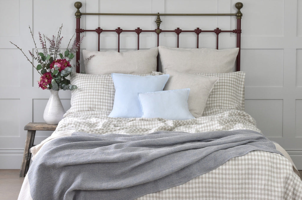 A Natural Gingham Linen Duvet Cover on a bed with Blue Linen Pillows and Cushions