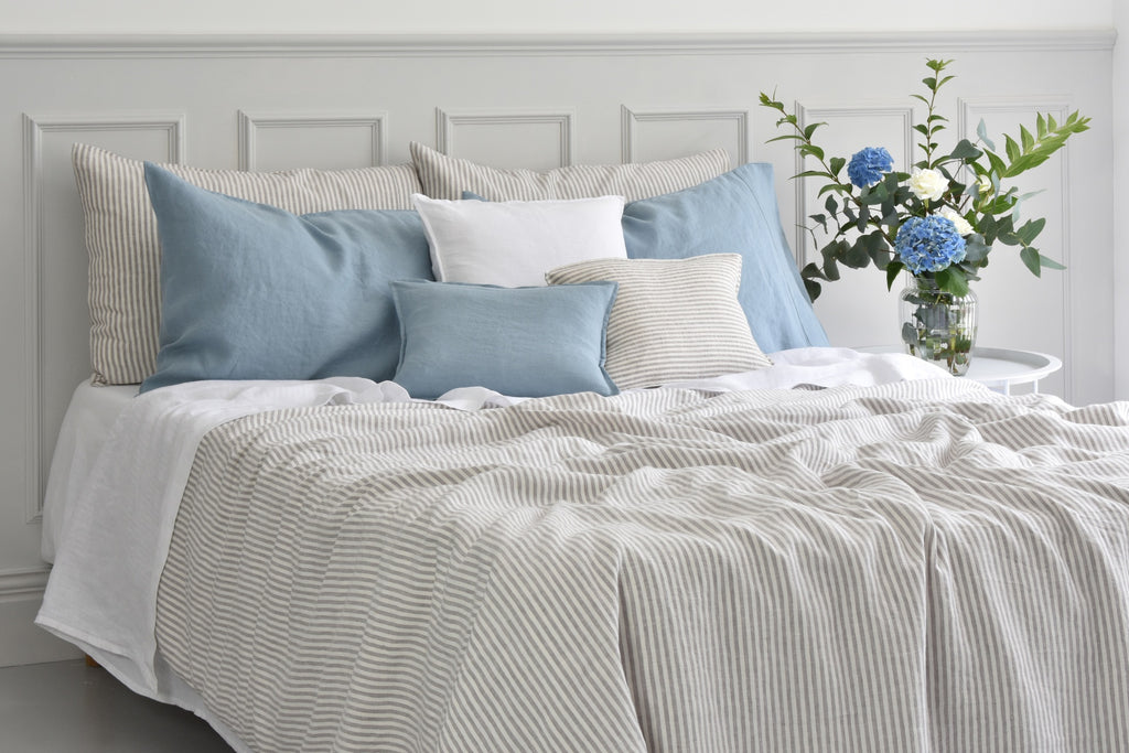 A Natural striped Linen Duvet Cover on a bed with Blue Linen Pillows and Cushions