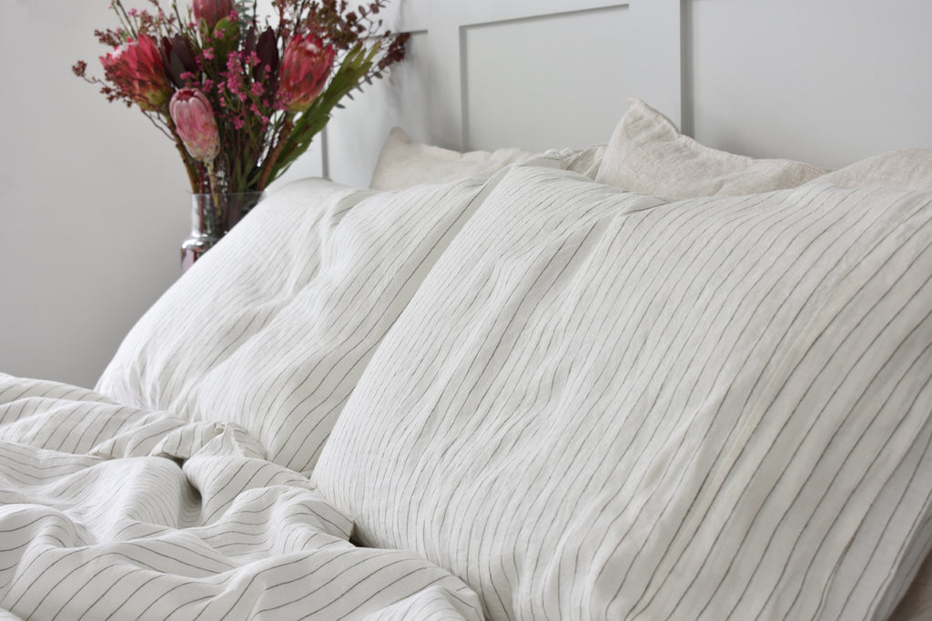 Two Stripe Linen Pillows on a Bed with White Linen Sheets