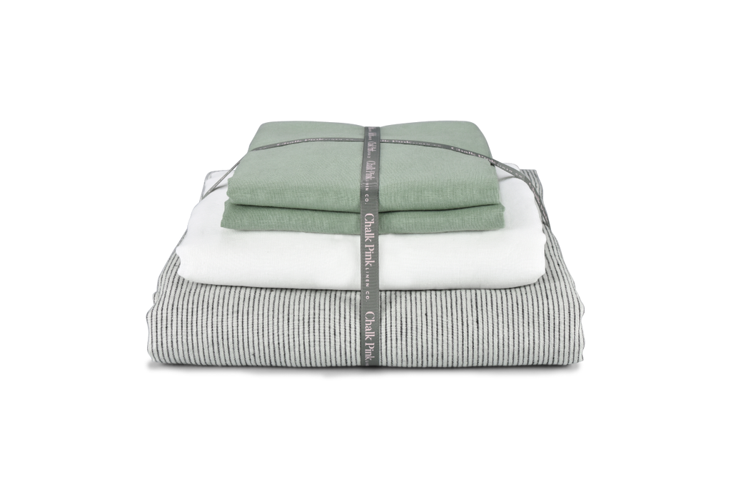 A Pinstripe Linen Duvet Cover with a White Linen Sheet and Green Linen Pillowcases Tied with Ribbon for a Gift