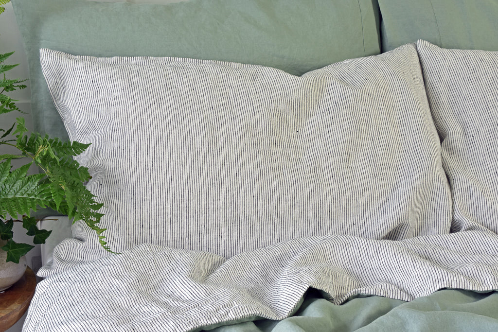 A Pinstripe Linen Pillowcase on a Bed with Sage Green Linen Bedding
