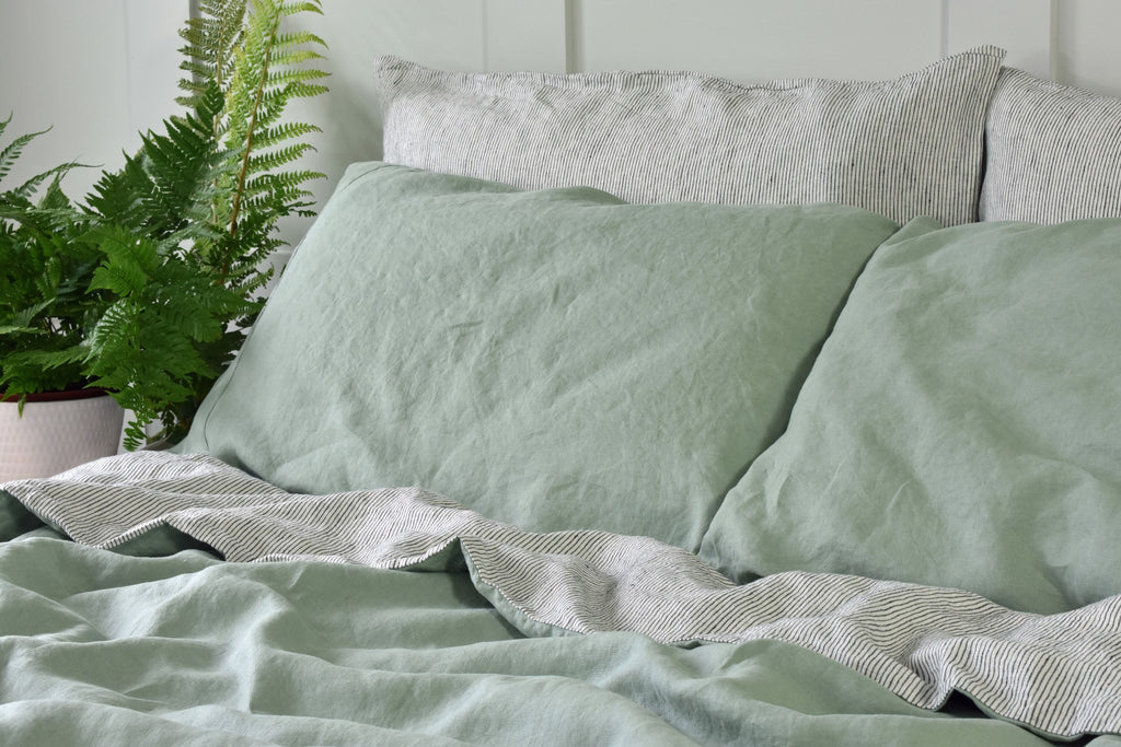 A Sage Green Linen Pillowcase on a Bed with Pinstripe Linen Pillowcases and Green Linen Duvet Cover