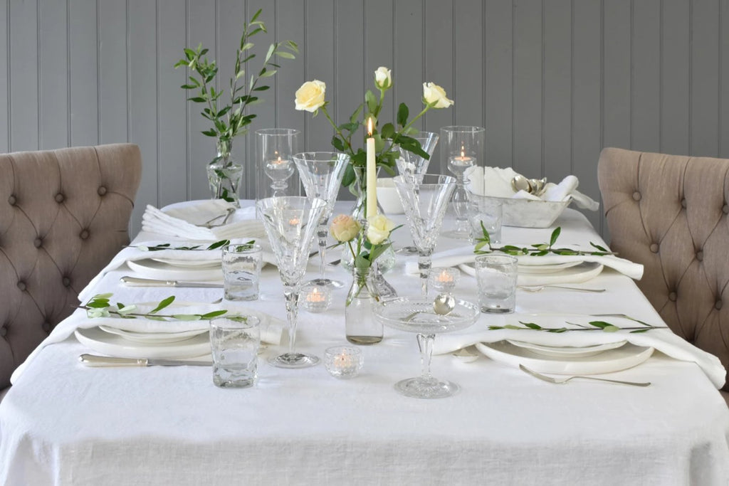 A white Linen Tablecloth on a Table with wine glasses and candles