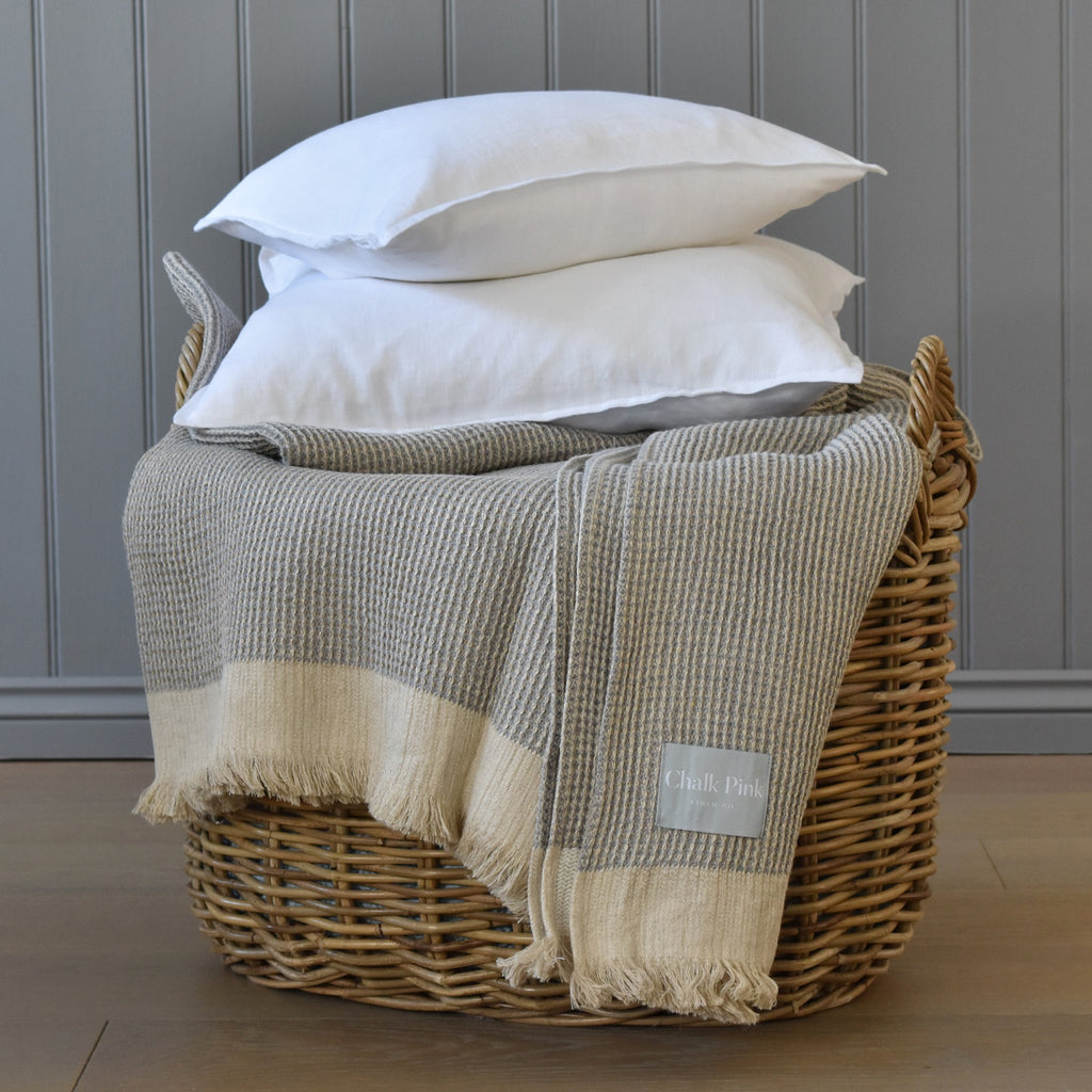 A Wicker Basket Full of Linen Throws and Linen Cushions
