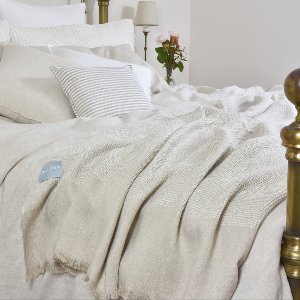 A Bed with Striped Bed Linen and an Oatmeal Coloured Natural Linen Throw