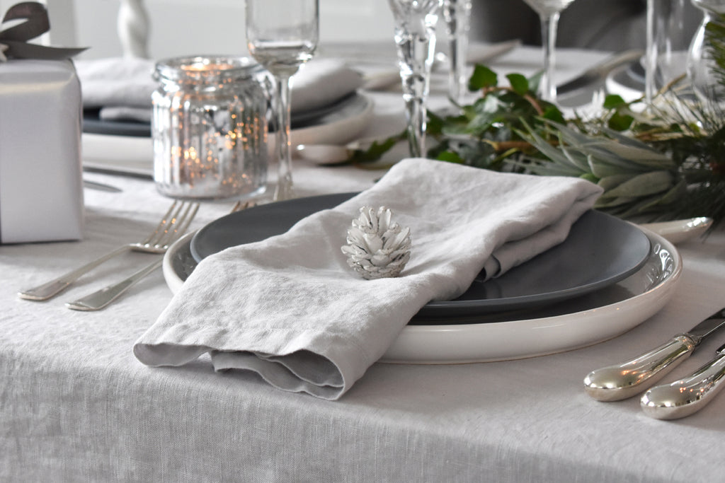 A Light Grey Flax Linen Napkin on a Christmas Table with a White Pine Cone