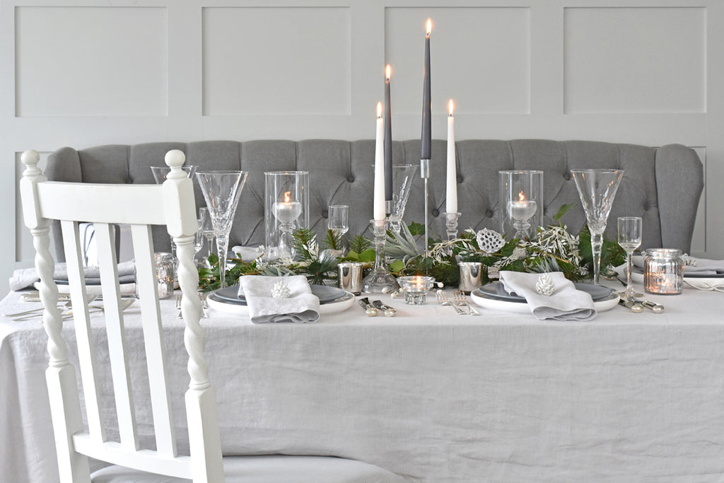 Elegant table setting with candles and greenery in a gray room.