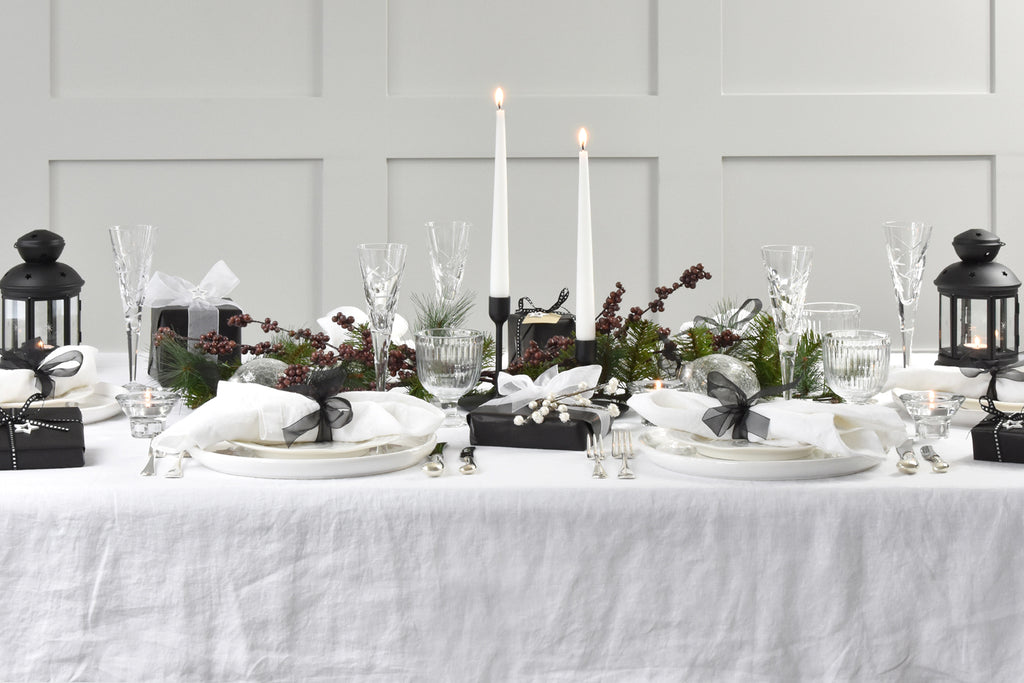 A Christmas Table with a White Linen Tablecloth and Monochrome Decorations