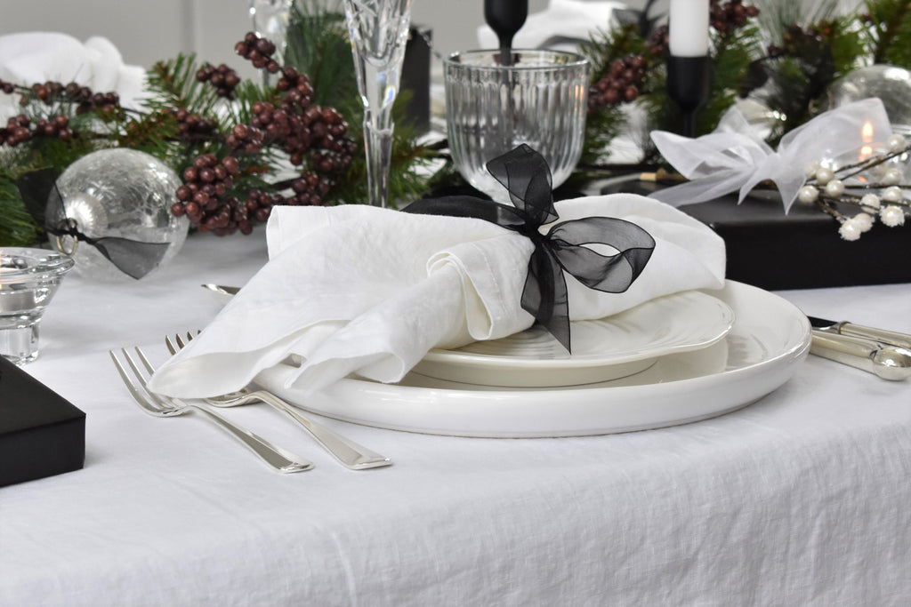 A White Linen Napkin on a Christmas Table with a Black Ribbon Tie