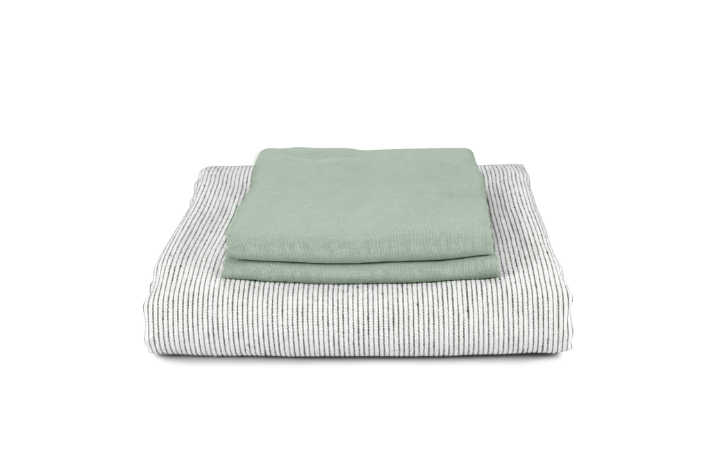 A Pinstripe Linen Bedding Set Folded with Green Linen Pillowcases on top