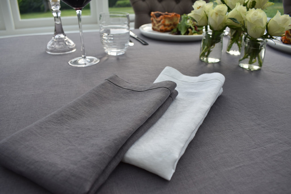 White Linen Folded Napkin on top of a Dark Grey Linen Tablecloth