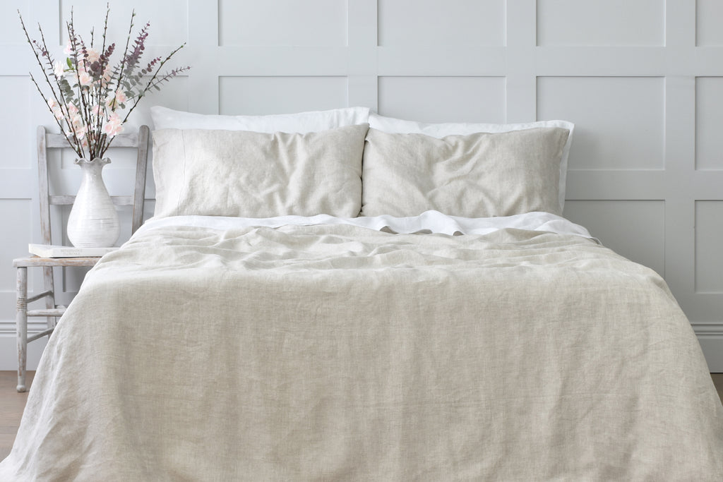 Natural Linen Bedding on a Bed in a Bedroom with a Grey Paneled Wall 