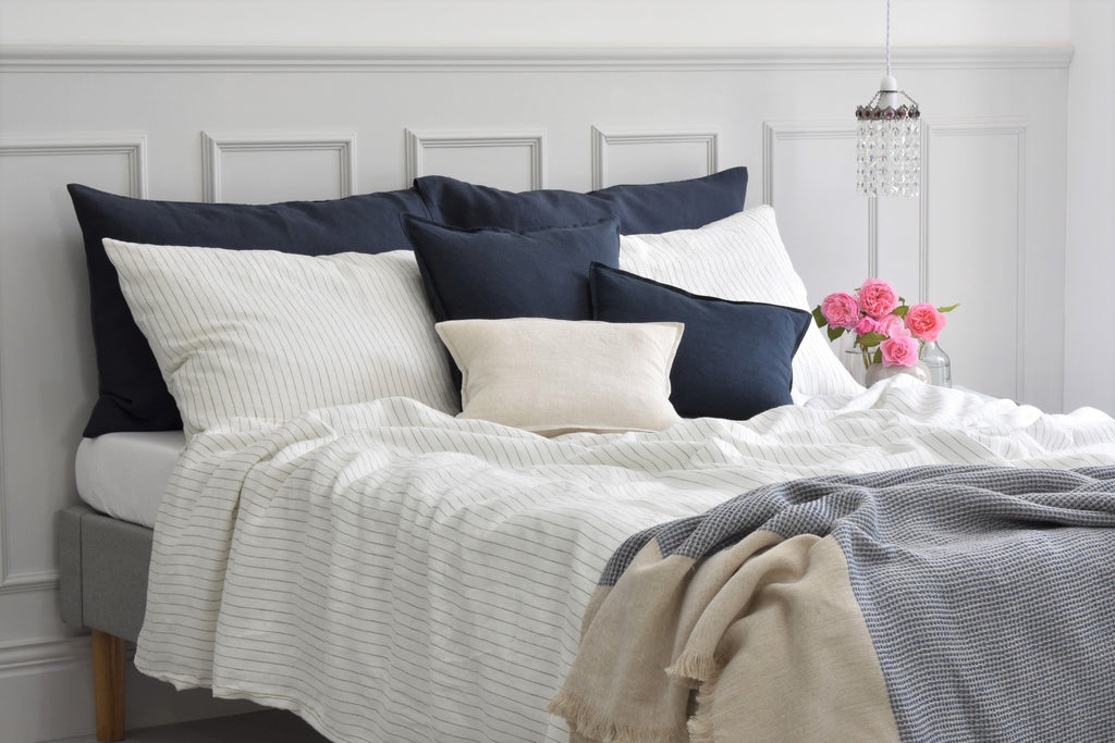 Pinstripe Linen Duvet Cover set on a bed with Navy Linen Cushions and White linen sheets on the bed