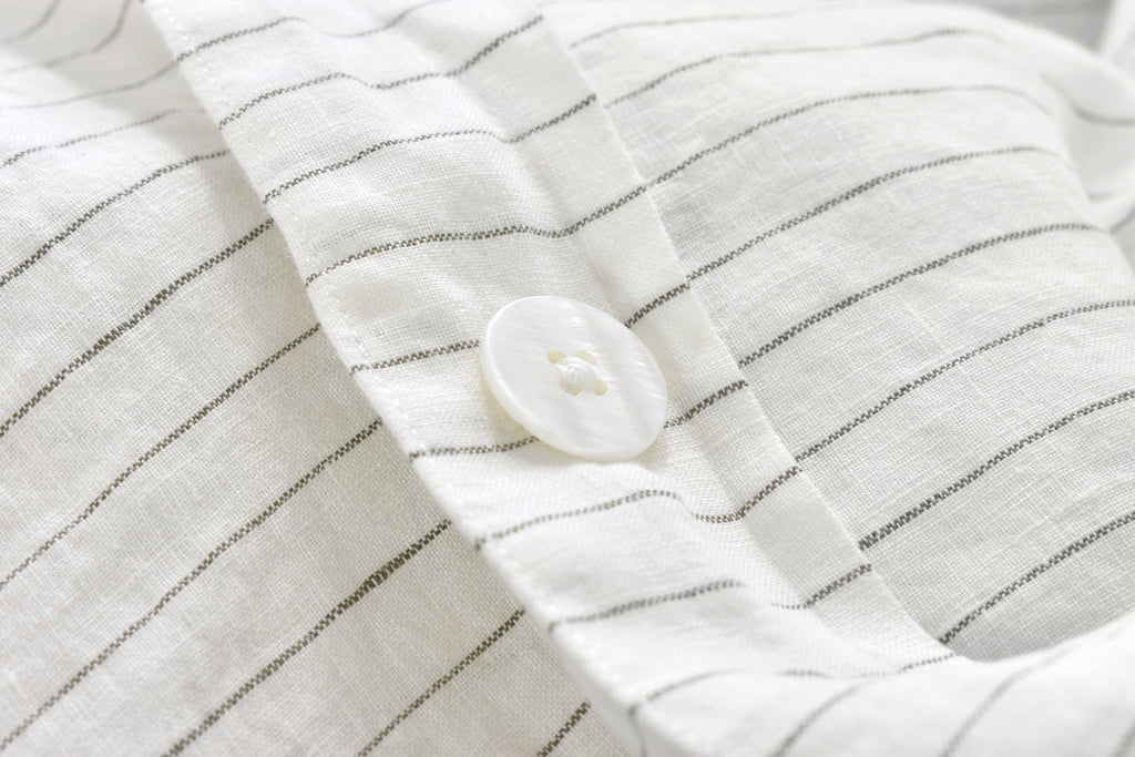 A Pinstripe Linen Duvet Cover Set on a Bed with a Pearl Button Fastening