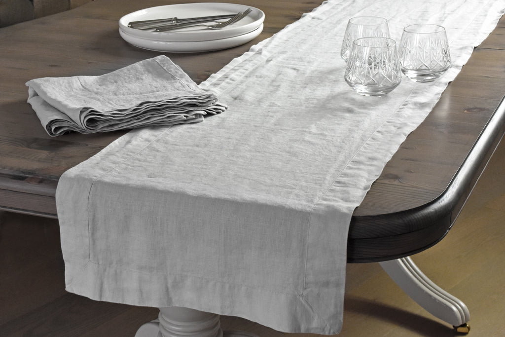 A Silver Grey Linen Table Runner on a Brown Oak Table with Silver Grey Linen Napkins and Whisky Glasses