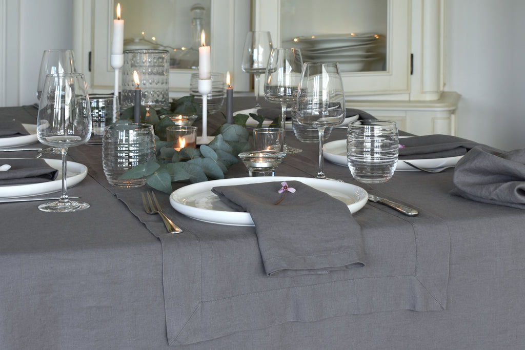 a Dark Grey Linen Tablecloth and Grey Linen Napkin on a Dining Table with Candles and Glassware