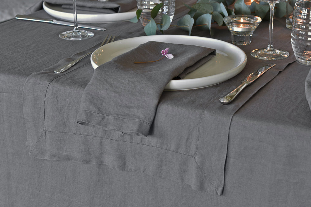 Dark Grey Linen Napkin with a Dark Grey Pure Linen Table runner on a Dining Table with Cutlery and Glassware
