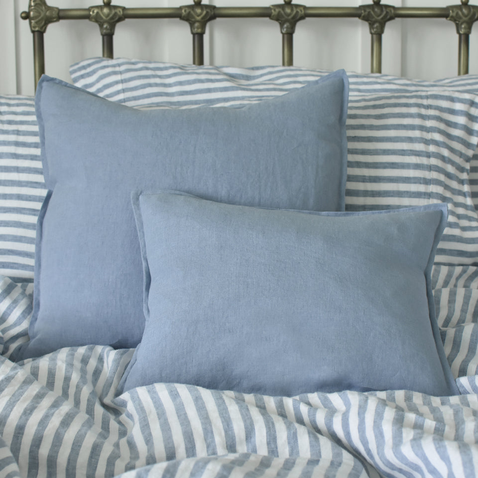 Small French Blue Linen Cushion on a Bed with Stripe Bedding